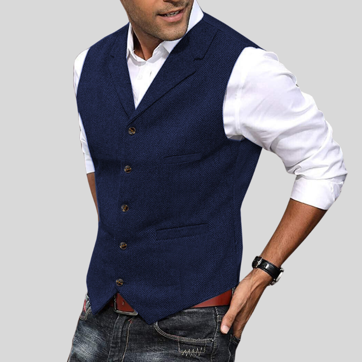 Gilet court sans manches bleu marine à boutons, coupe ajustée avec poches, porté sur une chemise blanche avec jean.