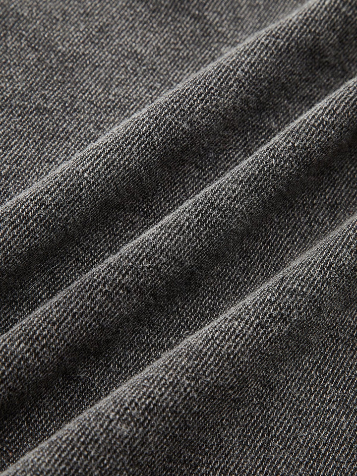 Gros plan sur le tissu en denim gris délavé, mettant en évidence la texture résistante, le tissage serré et la qualité du matériau pour un style moderne et durable.
