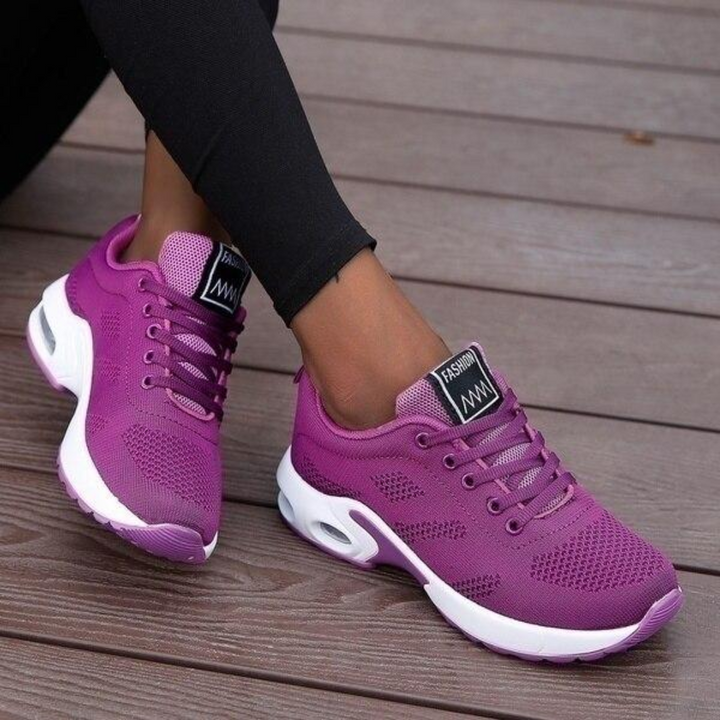 Baskets basses pour femme de couleur violette avec semelle blanche épaisse, portées avec un legging noir, au design moderne, respirant et confortable, idéales pour la marche et un usage quotidien.