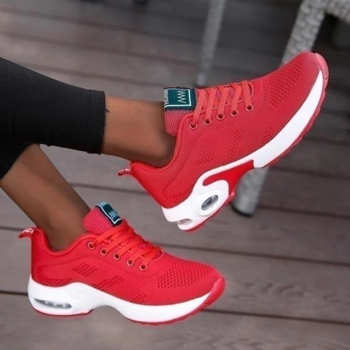 Baskets basses pour femme de couleur rouge avec semelle blanche épaisse et inserts amortissants, portées avec un legging noir, au design moderne, respirant et confortable, idéales pour la marche et le quotidien.