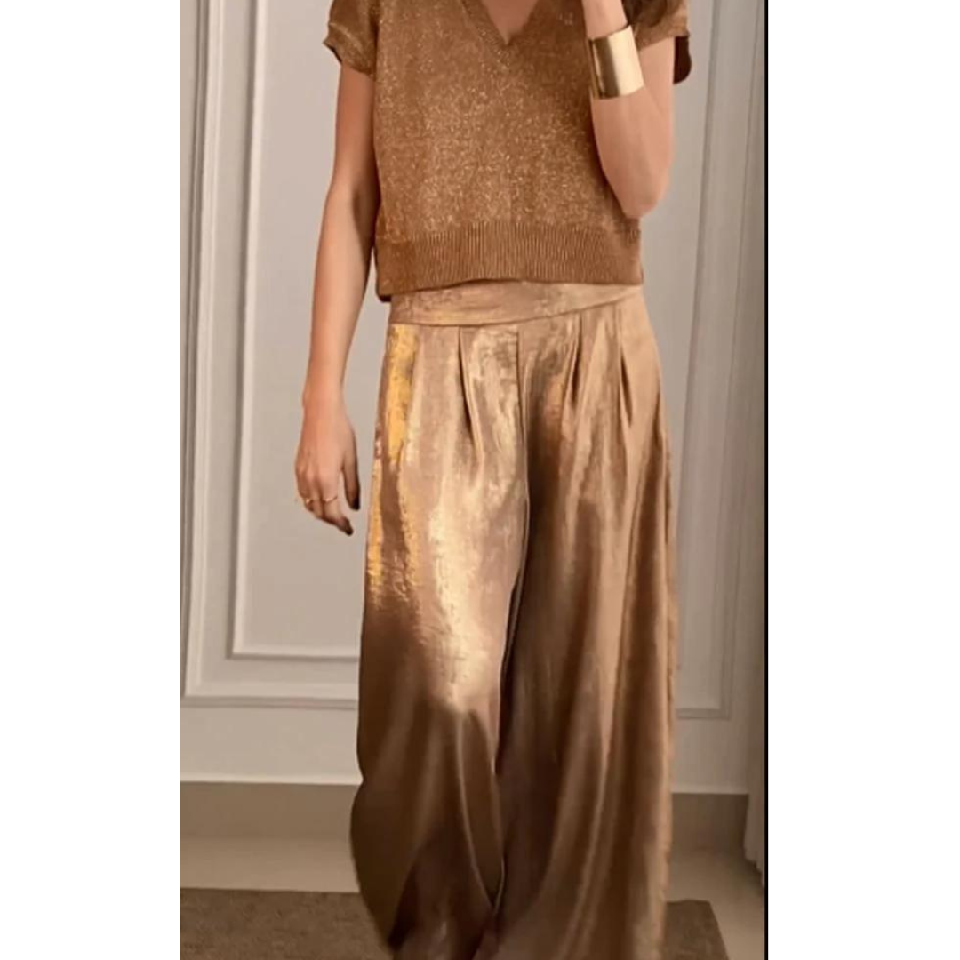 Un ensemble élégant pour femme, comprenant un haut en maille brillante de couleur dorée et un pantalon fluide assorti, au tissu lumineux et à la coupe ample, parfait pour une tenue chic et tendance.