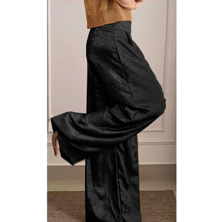 Un ensemble élégant composé d'un haut en maille dorée et d'un pantalon fluide noir, à la coupe large et au tissu brillant, offrant une allure moderne et sophistiquée.