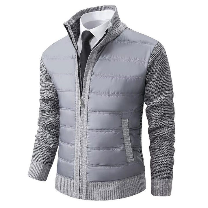 Veste moderne pour homme, avec un gilet matelassé gris clair sur le devant et un tricot gris texturé sur les manches et les côtés. Elle présente une fermeture éclair centrale, un col élégant et une coupe ajustée, idéale pour un look élégant et confortable lors des journées plus fraîches.