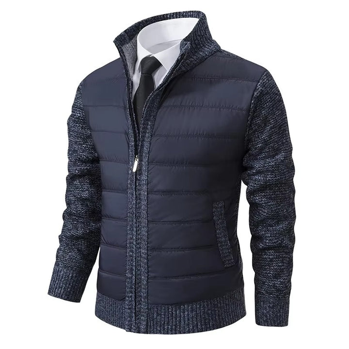 Une veste moderne pour homme, dotée d'un gilet matelassé bleu marine sur le devant et d'une maille texturée bleue sur les manches et les côtés. Elle présente une fermeture éclair centrale, un col élégant et une coupe ajustée, offrant confort et style pour les mois plus frais.