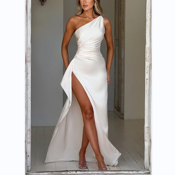 Une robe élégante à épaule unique, de couleur ivoire, avec une coupe fluide et une fente latérale sensuelle. Ce modèle sophistiqué est parfait pour une soirée ou un événement festif, offrant un look chic et moderne. Un choix idéal pour une occasion spéciale.