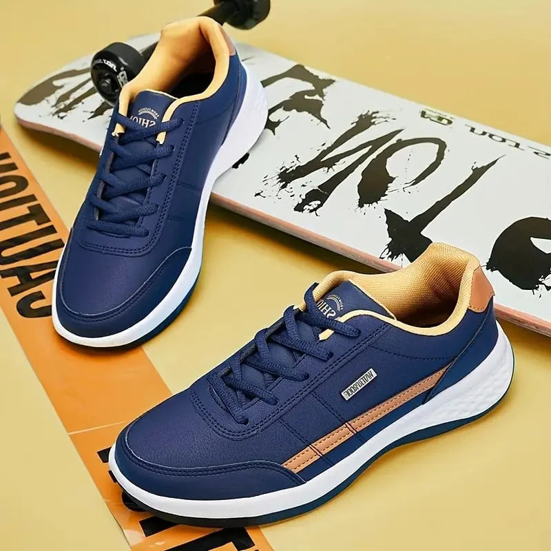 Chaussures décontractées pour homme Loïc modernes, baskets bleu marine avec détails camel, lacets assortis et semelle blanche confortable, présentées sur fond skateboard.