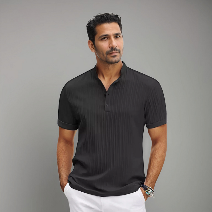 Homme portant un polo noir à manches courtes avec un col à boutons et un motif rayé discret, combiné à un style moderne et élégant. Un choix parfait pour un look à la fois décontracté et raffiné.