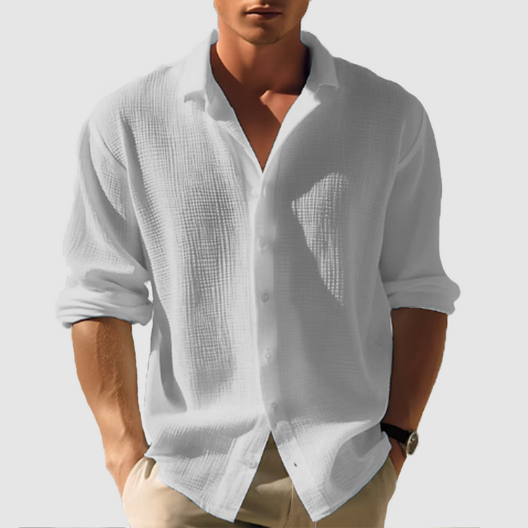 Homme portant la chemise Lothaire moderne à manches longues, en tissu texturé gris clair, col ouvert et coupe décontractée, idéale pour un style élégant et minimaliste.