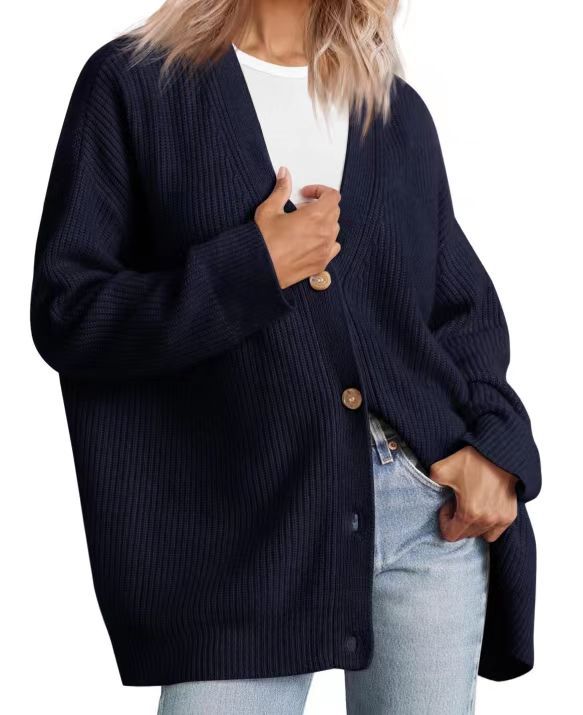 Femme portant un cardigan bleu marine à col en V, doté de gros boutons en bois et d’une coupe oversize. Le vêtement est superposé à un t-shirt blanc et associé à un jean clair, créant un style moderne, décontracté et confortable.