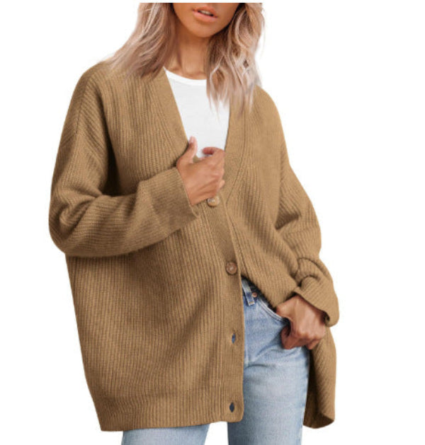 Femme portant un cardigan beige à col en V, doté de gros boutons en bois et d’une coupe oversize. Le vêtement est superposé à un t-shirt blanc et associé à un jean clair, créant un style moderne, décontracté et chaleureux.