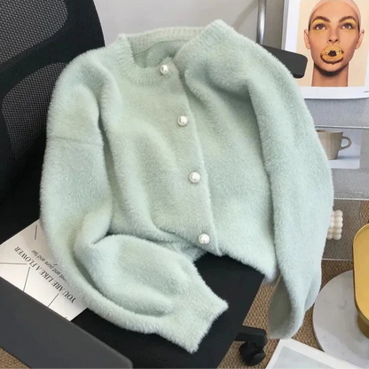 Cardigan chic pour femme Luna avec des boutons en perle, posé sur un bureau avec un design élégant et doux, parfait pour une tenue élégante et décontractée.