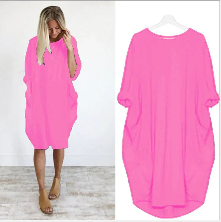 robe ample rose vif à manches 3/4, col rond, grandes poches latérales et ourlet arrondi, présentée portée et sur cintre.
