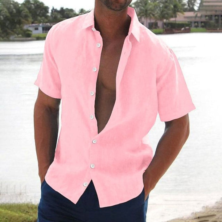 Homme portant la chemise Macon à manches courtes rose, légère et tendance, ouverte sur le devant, idéale pour un look estival décontracté au bord de l’eau.