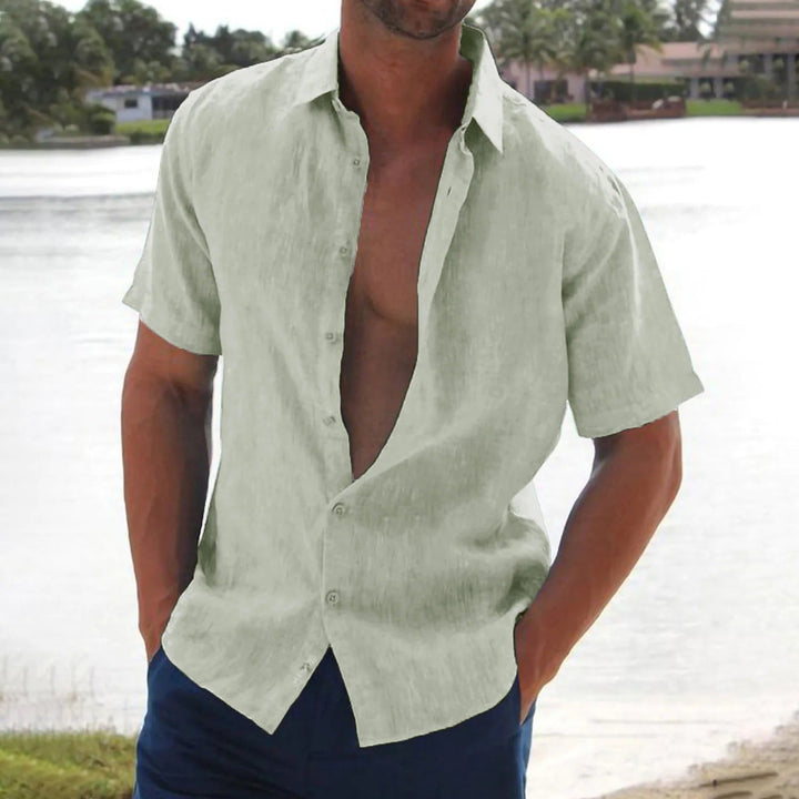 Homme portant la chemise Macon à manches courtes vert clair, légère et tendance, ouverte sur le devant, parfaite pour un look estival décontracté au bord de l’eau.