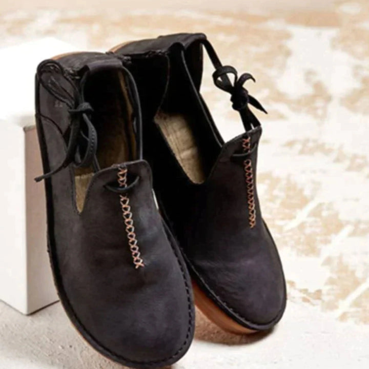 Chaussures confortables pour femme en cuir noir, avec une finition soignée et une décoration de couture rose. Un modèle élégant et pratique, parfait pour un look décontracté tout en assurant confort et style au quotidien.