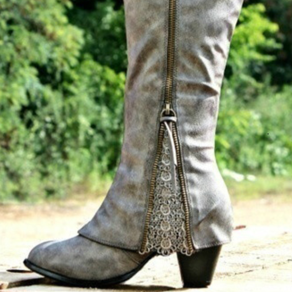 Bottes grises en cuir pour femme, à la coupe haute avec fermeture éclair décorée de dentelle sur le côté. Elles sont dotées d'un petit talon carré, offrant à la fois confort et style pour un look élégant et moderne.