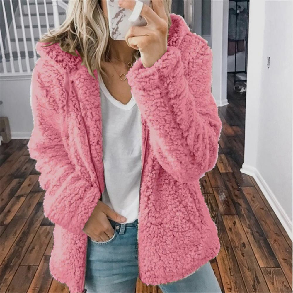 Femme portant la veste d’hiver courte Marie en fausse fourrure rose, chaude et douillette, associée à un t-shirt blanc et un jean, idéale pour un look tendance et confortable.