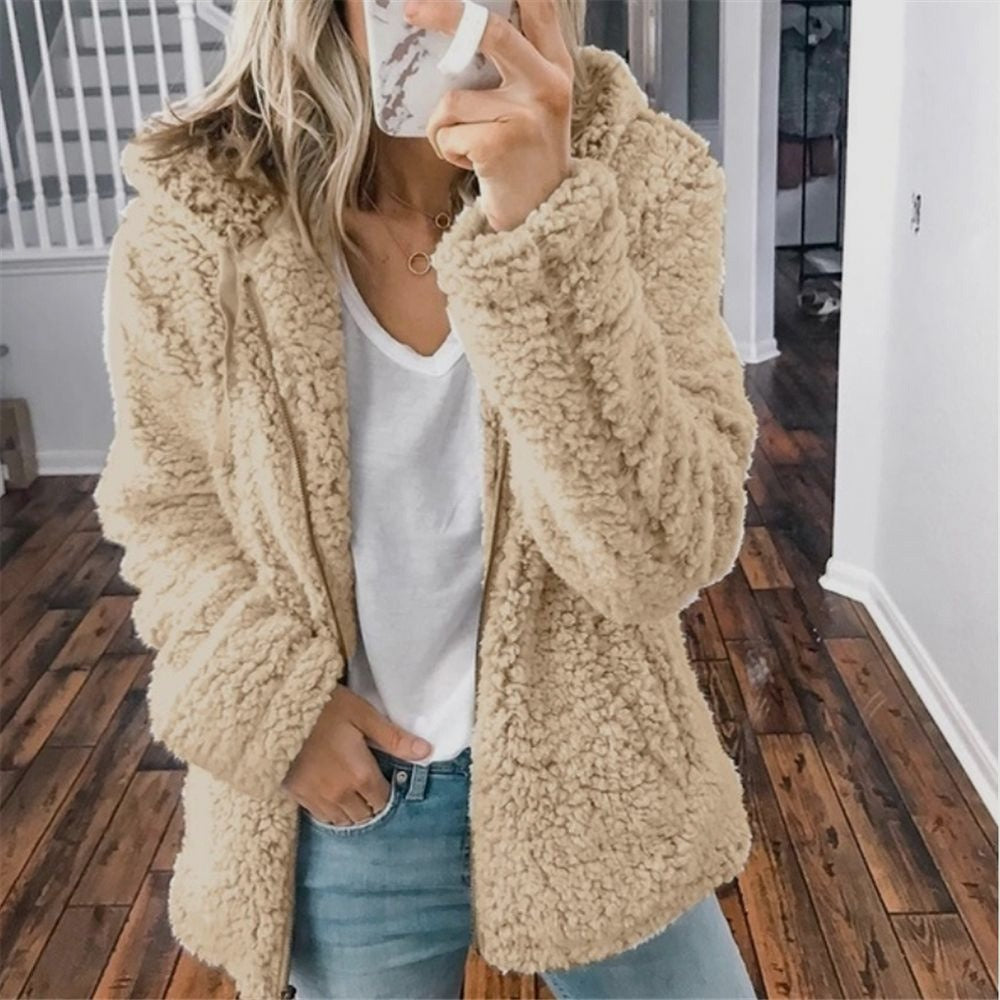 Femme portant la veste d’hiver courte Marie en fausse fourrure chaude, couleur beige, associée à un t-shirt blanc et un jean, pour un look élégant et cosy.