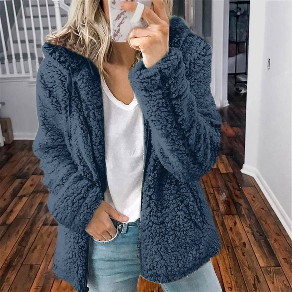 Femme portant la veste d’hiver courte Marie en fausse fourrure chaude, couleur bleu marine, associée à un t-shirt blanc et un jean, pour un look moderne et confortable.