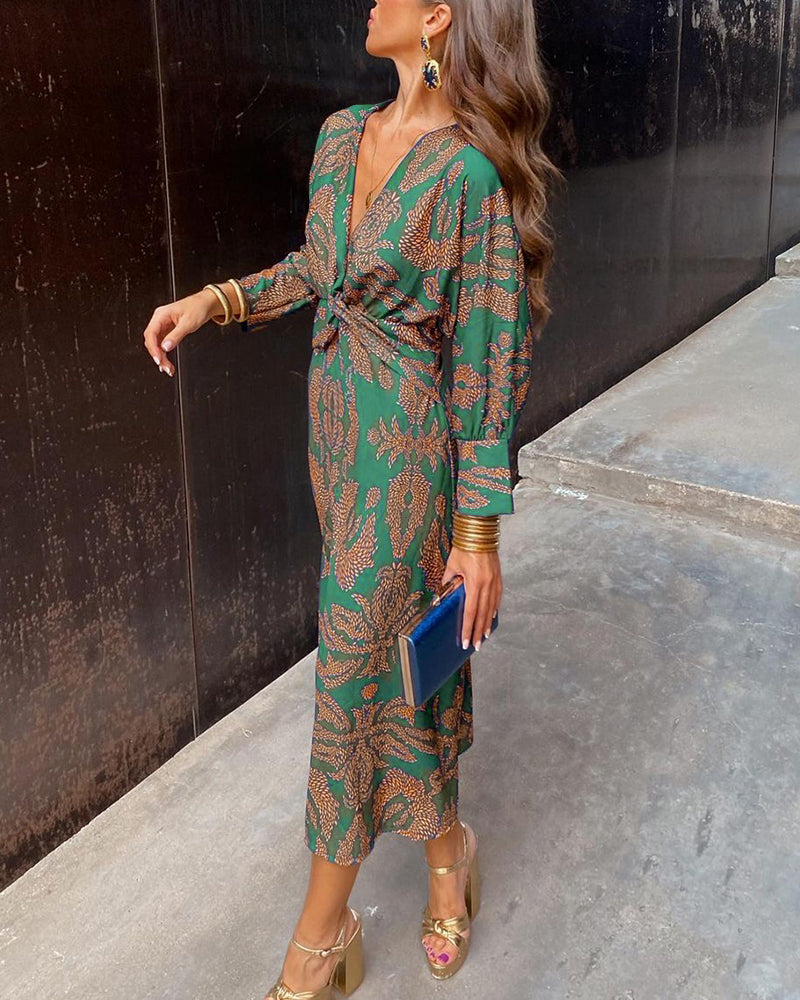 Robe longue Mariel pour femme, en vert avec motifs dorés, manches longues et décolleté en V noué à la taille, assortie à des sandales dorées et une pochette bleue, parfaite pour une soirée élégante.
