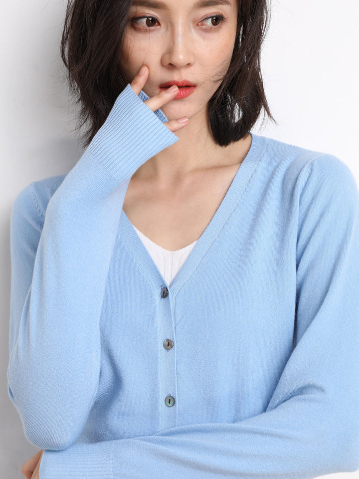 Femme portant un cardigan bleu ciel à col en V, doté de boutons assortis et d’une maille fine, superposé à un haut blanc. Le style moderne et délicat met en valeur une coupe douce, féminine et confortable.