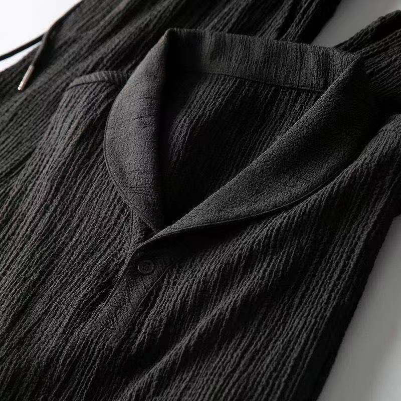 Détail de la chemise noire de l’ensemble d’été pour homme, mettant en valeur le col ouvert élégant et le tissu texturé léger pour un style moderne et raffiné.