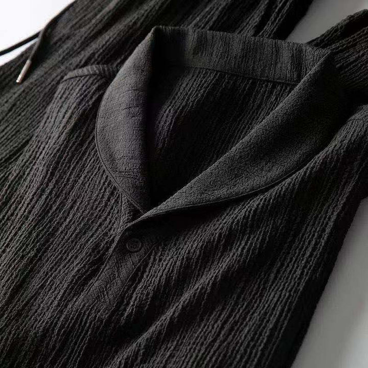 Détail de la chemise noire de l’ensemble d’été pour homme, mettant en valeur le col ouvert élégant et le tissu texturé léger pour un style moderne et raffiné.