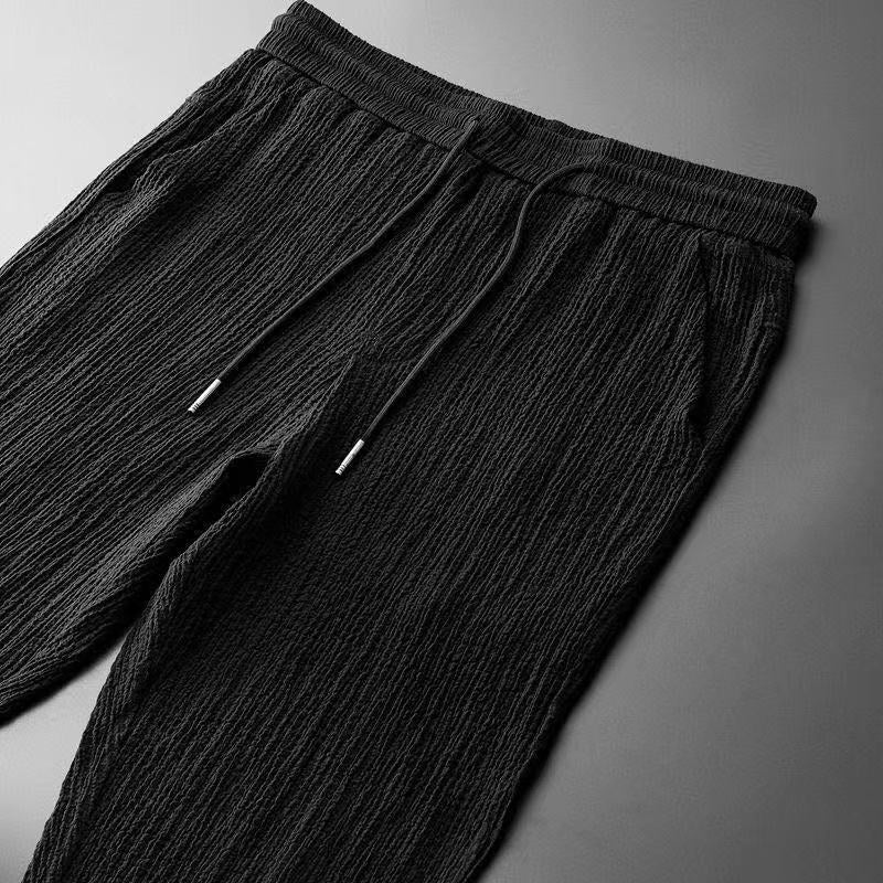 Pantalon noir de l’ensemble d’été pour homme, avec taille élastique et cordon de serrage, conçu dans un tissu léger et texturé pour un confort optimal et un style moderne.