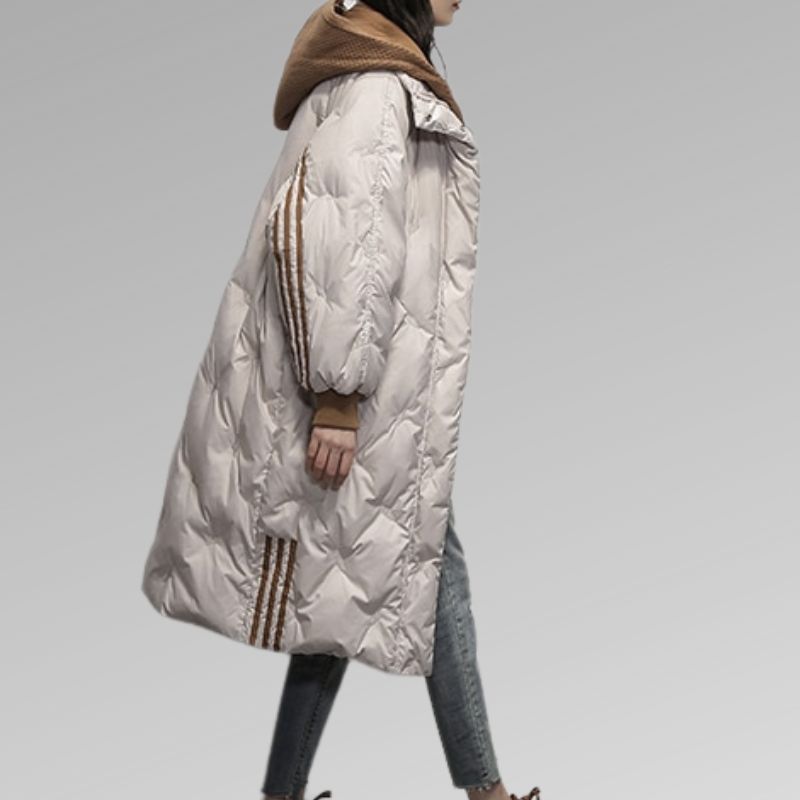 Michelle, doudoune longue beige pour femme vue de profil, manteau d’hiver chaud avec capuche marron et bandes décoratives sur les manches, style élégant et confortable.
