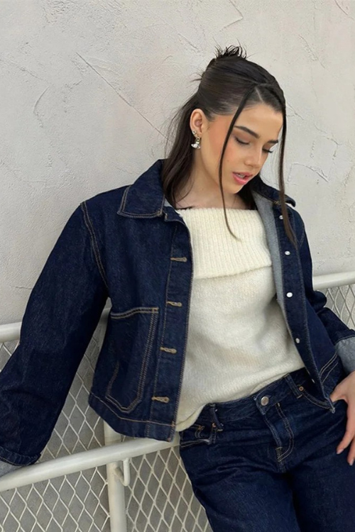 Ensemble femme moderne avec une veste en jean courte, parfaitement coupée pour un look tendance. La veste à boutons métalliques, associée à un pull blanc doux et un jean assorti, crée une silhouette chic et décontractée. Ce look urbain et intemporel est idéal pour un style quotidien élégant et confortable, avec des détails soignés qui apportent une touche de raffinement à votre tenue.
