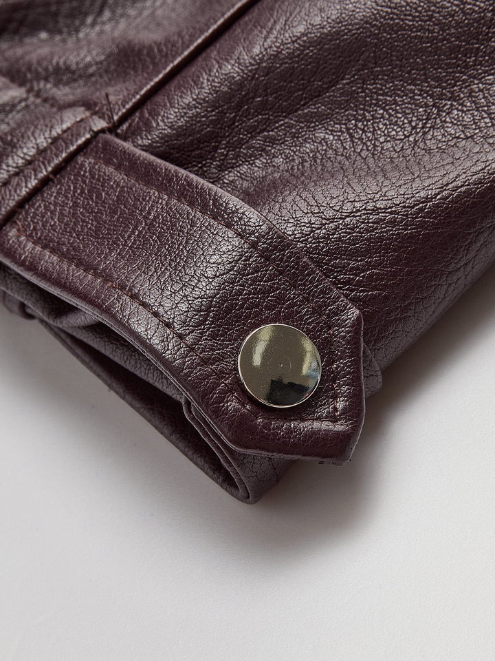 Gros plan sur le détail des manches avec boutons pression métalliques, mettant en valeur la finition soignée et la texture lisse du simili cuir bordeaux.
