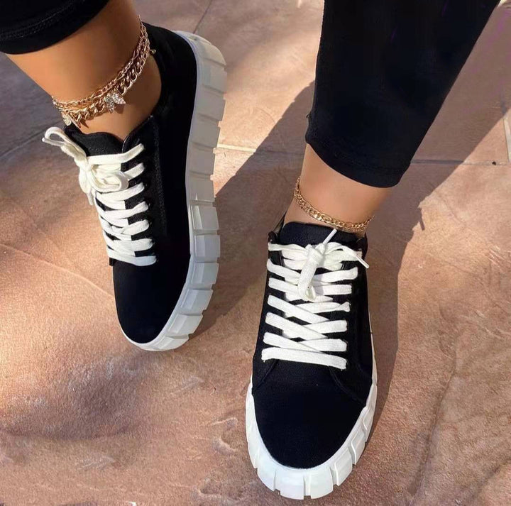 Baskets noires à plateforme avec une semelle épaisse blanche et des lacets blancs. Ce modèle moderne et élégant est parfait pour un look décontracté et tendance, offrant confort et style.
