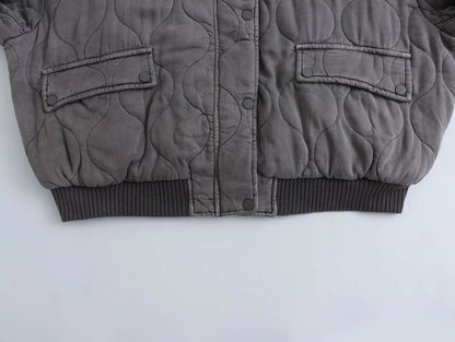 Détail du bas du blouson long pour femme "Nancy" en gris, avec un design matelassé, des poches à rabat et une finition côtelée au niveau de la taille. Parfait pour un look à la fois décontracté et élégant.