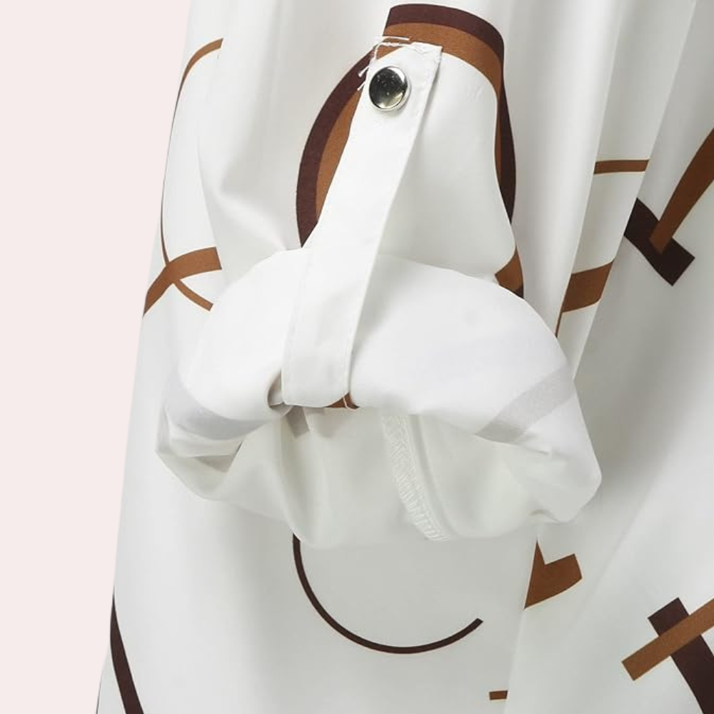 Gros plan sur la manche de la chemise femme Nivelle avec motif de lettres graphiques marron. Détail de manche retroussable avec patte boutonnée, offrant un style moderne, élégant et pratique.