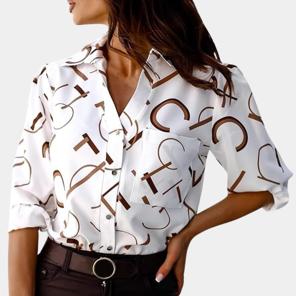 Chemise femme Nivelle blanche à lettres graphiques marron portée avec un pantalon foncé. Modèle élégant avec col classique, poche poitrine et manches retroussées, parfait pour un look tendance et moderne.