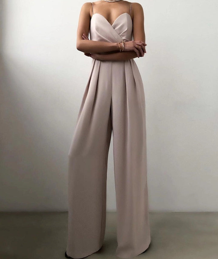Combinaison longue beige clair à fines bretelles, décolleté cœur croisé et taille marquée, avec pantalon large fluide, portée par un mannequin sur fond neutre.