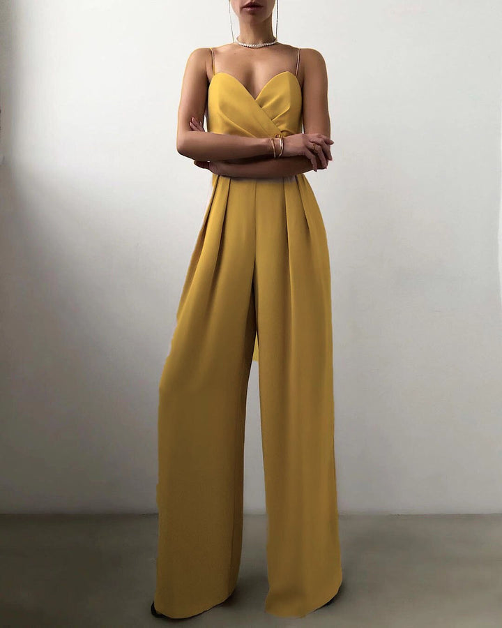 Combinaison longue jaune moutarde à fines bretelles, décolleté cœur croisé et taille marquée, avec pantalon large fluide, portée par un mannequin sur fond neutre.