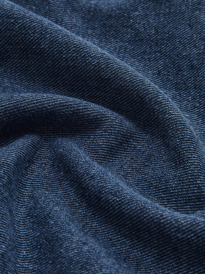 Détail du tissu en denim bleu de la veste en jean 'Nyselle' pour femme. Ce zoom met en évidence la texture douce et la finition de qualité du jean, offrant à la veste une allure moderne et confortable, idéale pour un style décontracté et élégant.