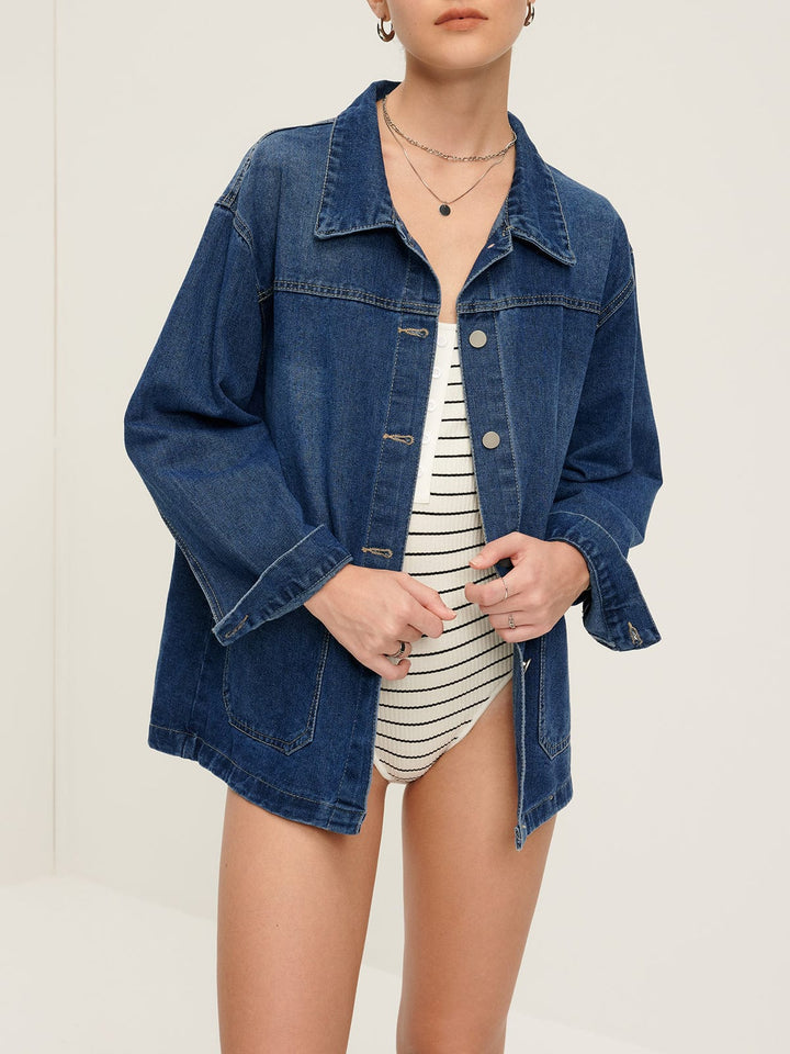 Veste en jean 'Nyselle' pour femme, portée ouverte avec des boutons métalliques, offrant une coupe décontractée et moderne. Le modèle associe la veste en denim bleu avec un haut à rayures, créant un look casual et stylé, parfait pour une tenue quotidienne.