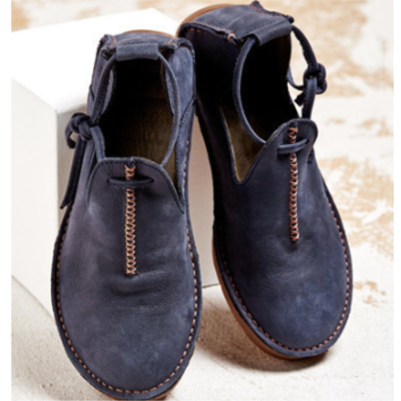 Chaussures d’automne pour femme en cuir bleu foncé, au design moderne et minimaliste, avec coutures contrastées apparentes, ouverture sur le dessus et semelle plate confortable, présentées sur un fond clair.