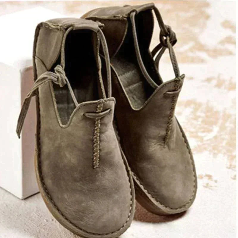 Chaussures d’automne pour femme en cuir gris taupe, style moderne et épuré, avec coutures artisanales visibles, ouverture souple sur le dessus et semelle plate confortable, présentées sur un fond clair.