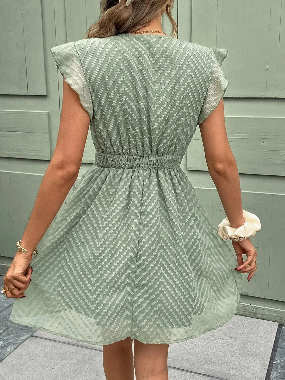 Robe mini d'été à col V pour femme, avec des volants délicats et une taille élastiquée qui offre un ajustement confortable. Son tissu léger à motif chevron et sa coupe fluide en font la pièce parfaite pour un look estival à la fois tendance et féminin.