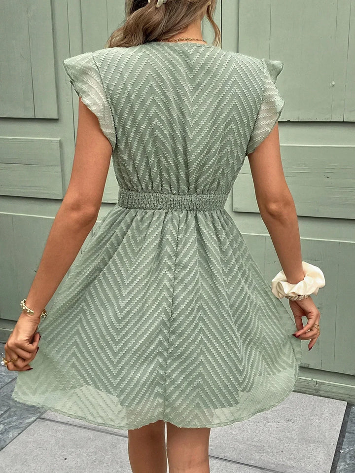 Robe mini d'été à col V pour femme, avec des volants délicats et une taille élastiquée qui offre un ajustement confortable. Son tissu léger à motif chevron et sa coupe fluide en font la pièce parfaite pour un look estival à la fois tendance et féminin.