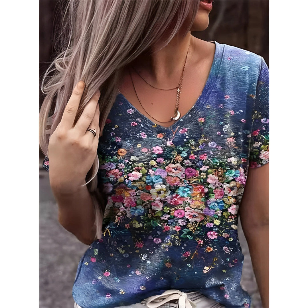 T-shirt bleu effet denim à col V, avec large imprimé floral multicolore sur le devant, porté par un mannequin.