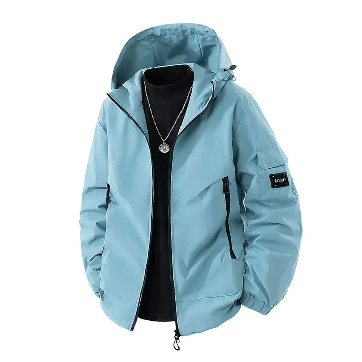 Veste d'hiver pour homme de couleur bleue claire, avec capuche ajustable. Elle est équipée de poches zippées sur les côtés et d’un logo sur la manche. Parfaite pour les journées fraîches et modernes, avec un look décontracté et tendance.