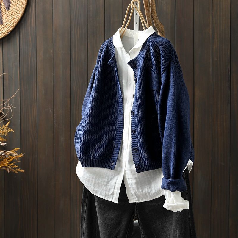 Cardigan oversize pour femme de couleur bleu marine, suspendu sur un cintre au-dessus d’une chemise blanche ample. Le modèle présente une maille texturée, une coupe large et des boutons assortis, offrant un style moderne, décontracté et élégant.