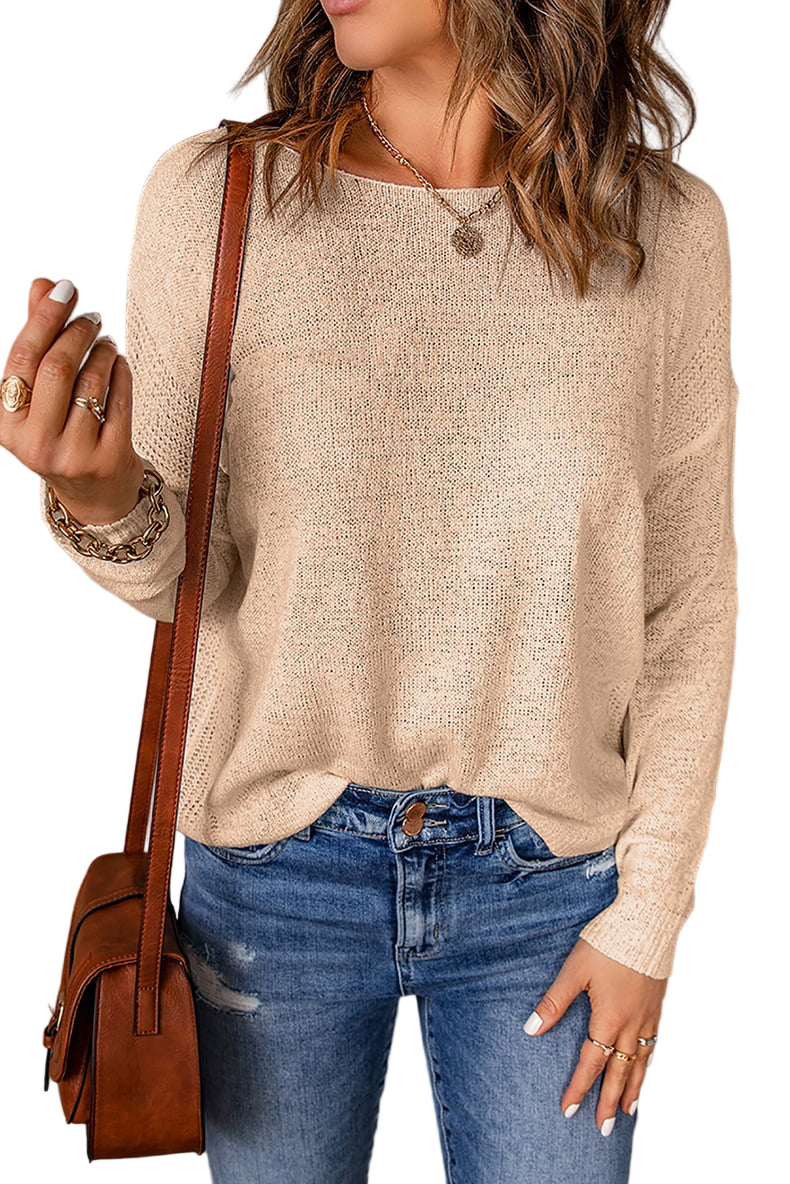 Une femme portant un pull décontracté à coupe ample, associé à un jean déchiré. Elle porte un sac en cuir en bandoulière et des bijoux superposés, affichant un look chic et décontracté.