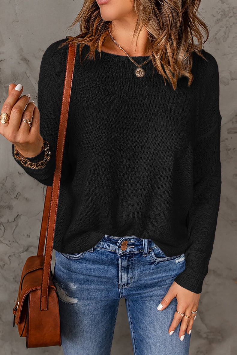 Une femme portant un pull décontracté à coupe ample, associé à un jean déchiré. Elle accessoirise avec un sac en cuir en bandoulière et des bijoux superposés, dégageant un look stylé et décontracté.