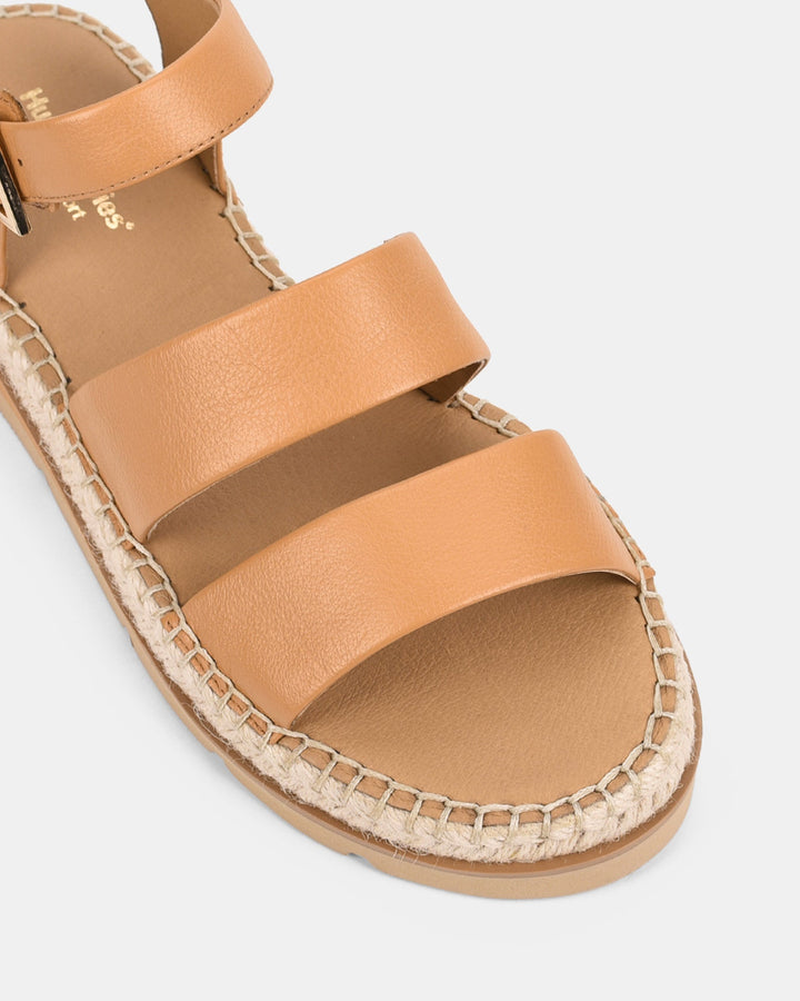 Gros plan sur des sandales pour femmes couleur caramel, mettant en valeur les deux brides larges et la finition tressée de la semelle style espadrille. Design confortable et tendance, idéal pour la saison estivale.