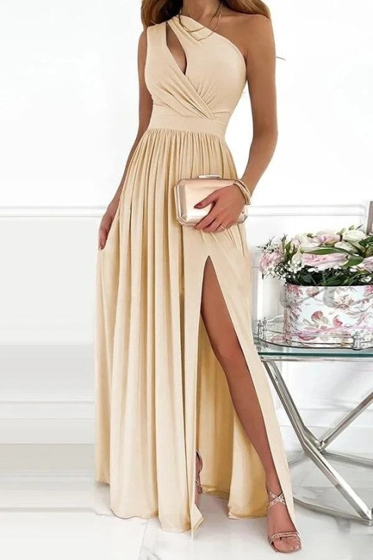 Robe beige élégante à épaule unique, avec une fente sexy sur le côté. Parfaite pour les occasions spéciales, elle est accompagnée d'une pochette métallique et de sandales à talons, créant une silhouette sophistiquée et féminine.